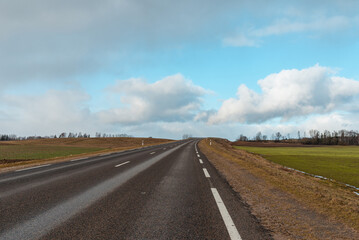 Empty road asphalt landscape among green spring meadows , blue sky,white clouds.