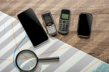 Magnifying glass, city map and set of different mobile phones for investigation