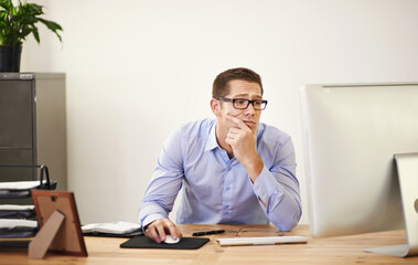 Naklejka premium Why did I leave this for the end of the day. Shot of a businessman looking uncertain as he works on his computer.