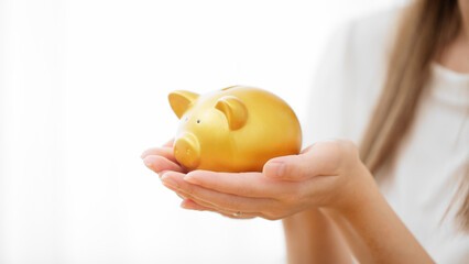 ブタの貯金箱を持つ若い女性