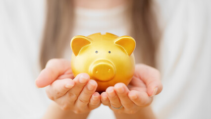 ブタの貯金箱を持つ若い女性