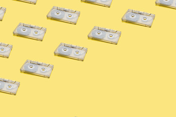 Seamless pattern made of audio cassette tapes on yellow background. Retro style. Vintage wallpaper. 90s nostalgia.