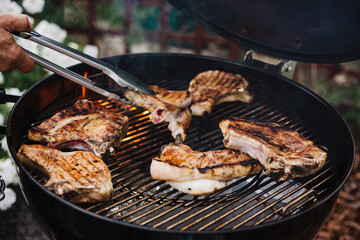 Close-up of grilling steaks of meat on barbecue with open flames. Backyard BBQ