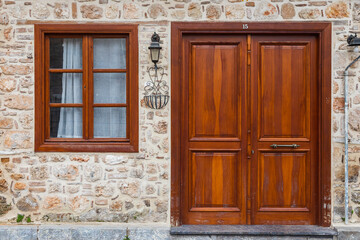 Close-up wall of a stone house with wooden door,  windows . Old european architecture