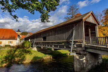Fototapeta na wymiar Roofed wooden bridge over the river Ilm in Buchfart, Thuringia, Germany.