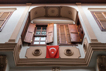 close-up of the Turkish national flag hanging on an ancient stone building with wooden windows and bars, view from below