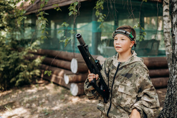 Boy with a weapon in his hand playing laser tag shooting game in outdoor. War simulation game