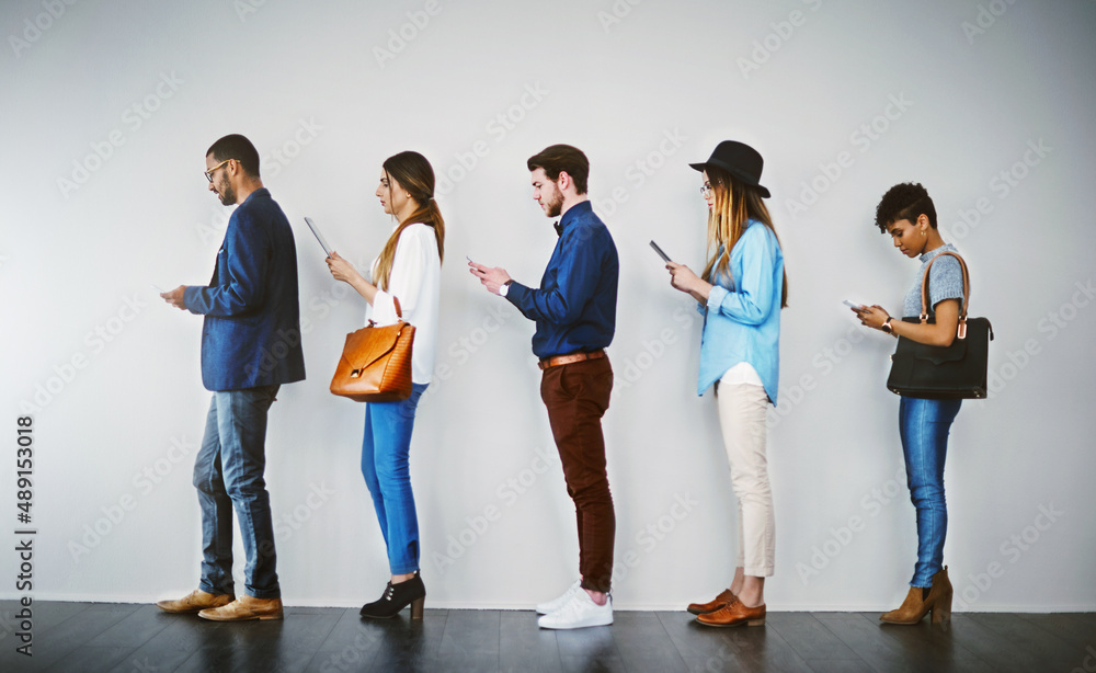 Leinwandbilder Getting last minute tips online before the interview. Shot of a group of businesspeople using wireless technology while waiting in line.