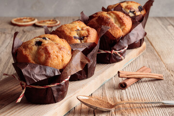Close-up view of four homemade delicious muffins and cinnamon on wooden background. Selective focus.