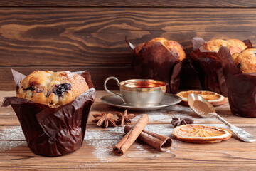 Top view of homemade delicious muffins with spoons and cinnamon on wooden background. Selective focus.