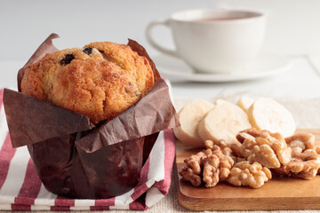 Close-up view of homemade delicious muffin and banana and cup of tea on linen background. Selective focus.
