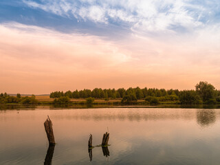 Red sunset on a lake, river or pond with blue sky and clouds.