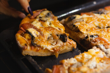 A handmade pizza pie was cut using a knife by a woman. Closeup food picture