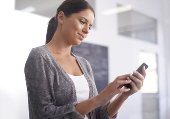 Staying in touch every minute of the day. A beautiful young woman using her smartphone at the...