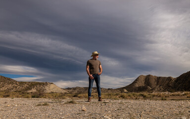 Adult man in cowboy hat standing against mountains in Tabernas desert. Almeria, Spain