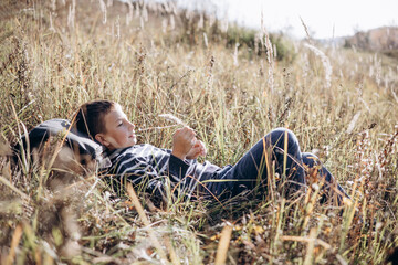 Autumn portrait of teenager boy with backpack lying on grass. Happy child with backpack resting...