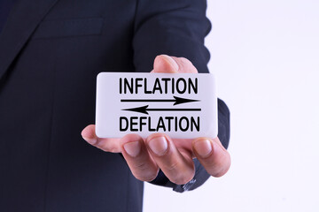 businessman holding banner with inflation and deflation concept