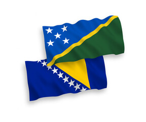 National vector fabric wave flags of Solomon Islands and Bosnia and Herzegovina isolated on white background. 1 to 2 proportion.