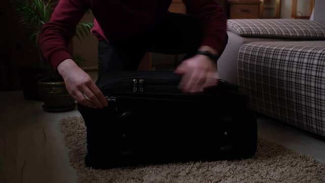 A young guy opens a suitcase and collects things in a hurry because of the hostilities