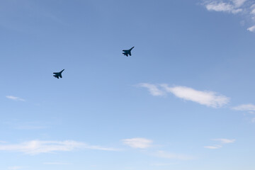 Two combat aircraft against a blue sky with clouds.