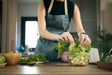 Young woman making vegetable salad on kitchen at home. Healthy lifestyle concept.