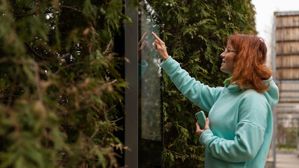 A woman uses a street self-service terminal for contactless payment with a smartphone.