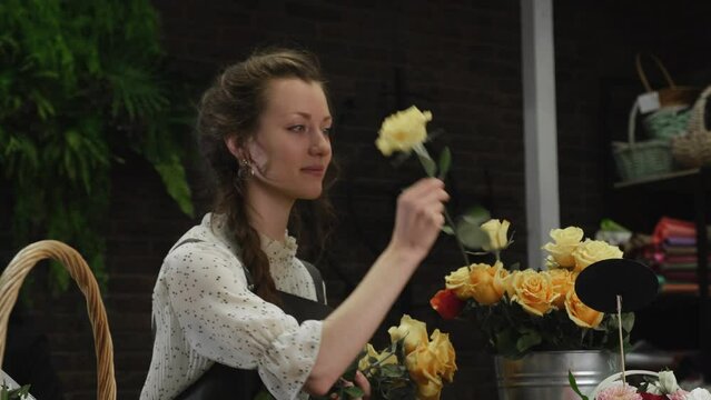 Girl florist collects a bouquet of roses