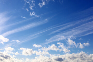 Obraz premium Blue sky covered with white cumulus and cirrus clouds. Spring cloudscape, beautiful weather background