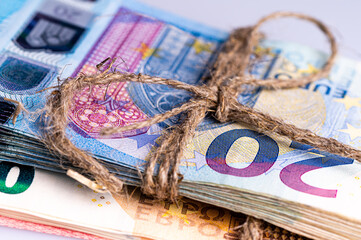 stack of euro banknotes tied with burlap string, close-up, wealth and prosperity concept