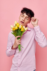 pretty man in a pink shirt with a bouquet of flowers gesturing with his hands model studio