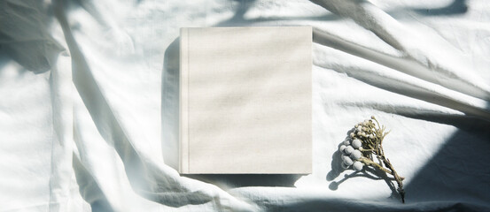 自然光と影が差し込む、白のファブリックに置かれた本