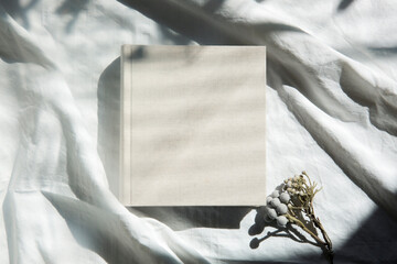 自然光と影が差し込む、白のファブリックに置かれた本