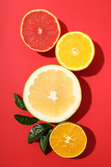 Obraz na płótnie Canvas Citrus fruits halves with leaves on red background