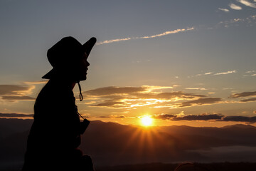 silhouette Young woman traveler looking at sunrise over the mountain.