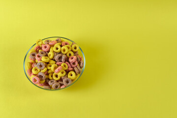 a plate with multicolored cereal rings on a yellow background
