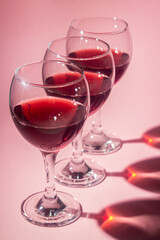 Glasses of red wine on a pink background. Alcoholic drink.