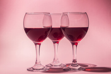 Glasses of red wine on a pink background. Alcoholic drink.