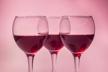 Glasses of red wine on a pink background. Alcoholic drink.