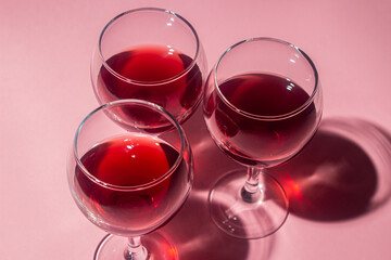 Glasses of red wine on a pink background. Alcoholic drink.