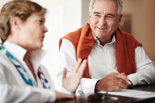 Enjoying A Conversation At The Reception Desk. A Senior Man And His Wife Filling Out Forms At A Hotel Reception Desk.