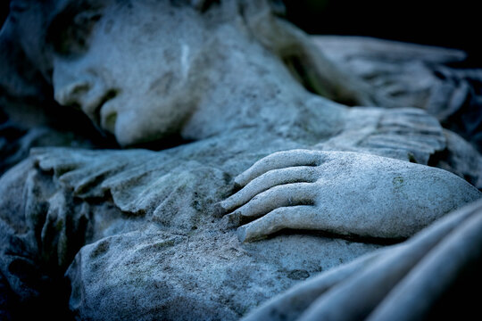 Fragment of an ancient statue of end of human life. Beautiful dead woman light on the bed. Selective focus on hand. Horizontal image.