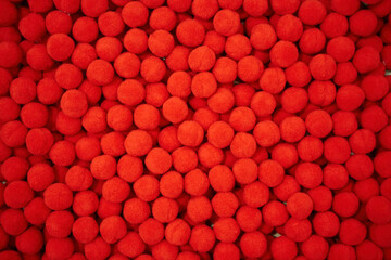 Soft fluffy ball as accessories for sewing production. Lots of red objects.