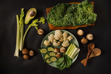 Green healthy vegetables and fruits on a black background. 