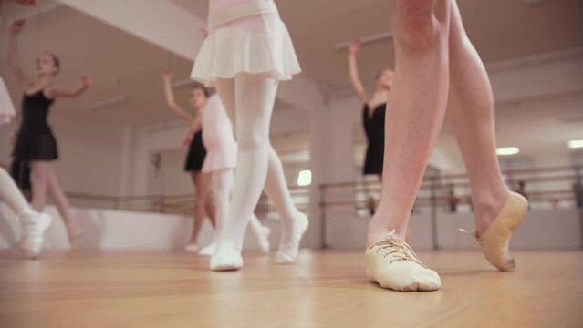 Ballet training - group of little ballerina girls following movements of their trainer