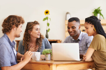 In good company. A group of friends sitting together in a coffee shop with a laptop.