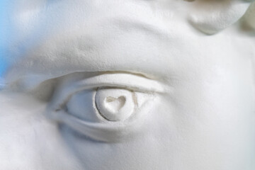 The eye of a statue with a heart instead of a pupil. closeup
