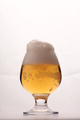 a glass with light beer and foam on a white background