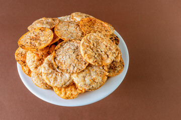 Brown rice chips on a plate on a brown background