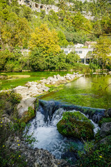 Sorgue river and limestone mountains in Fontaine de Vaucluse village in Provence, France on a summer day