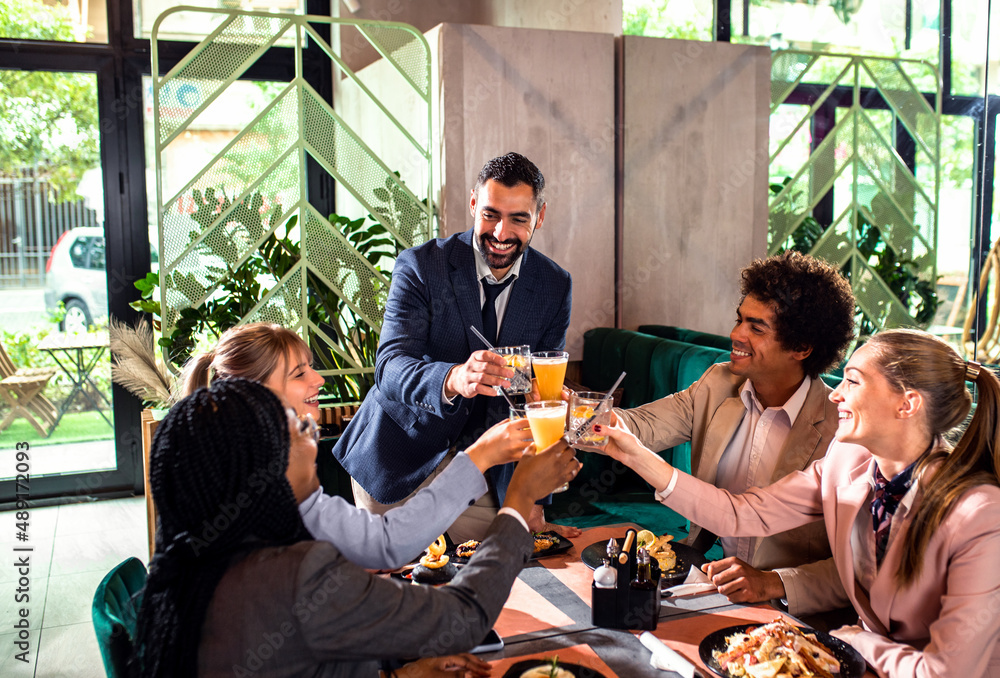 Wall mural group of businesspeople in a restaurant toasting at business lunch.